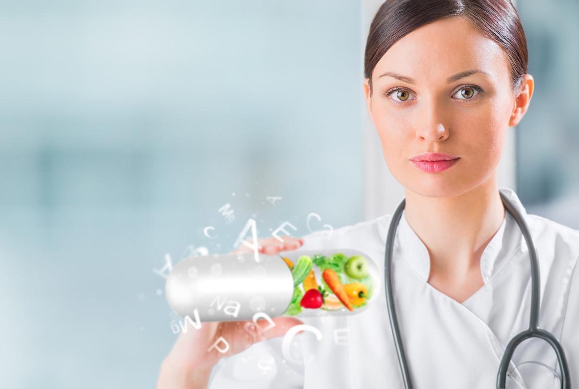 Doctor presenting a capsule full of fresh fruit and vegetables, symbolising natural nutrition